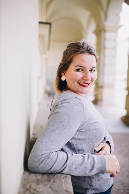 Foto ritratto di una giovane donna sorridente in piedi contro il muro