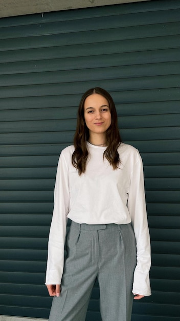 Portrait of a smiling young woman standing against wall