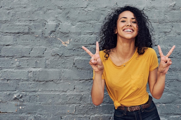 Photo portrait of a smiling young woman standing against wall