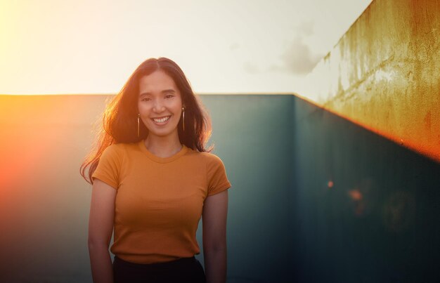 Portrait of a smiling young woman standing against wall