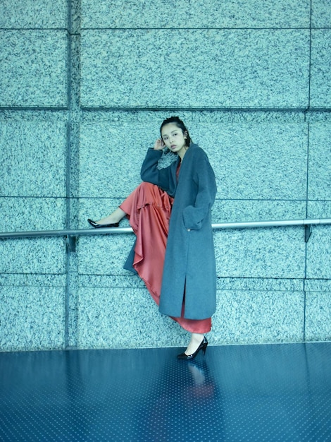 portrait of a smiling young woman standing against wall