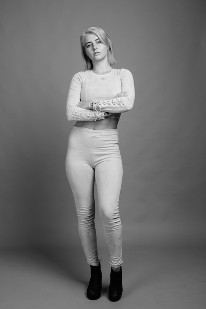 Portrait of smiling young woman standing against wall