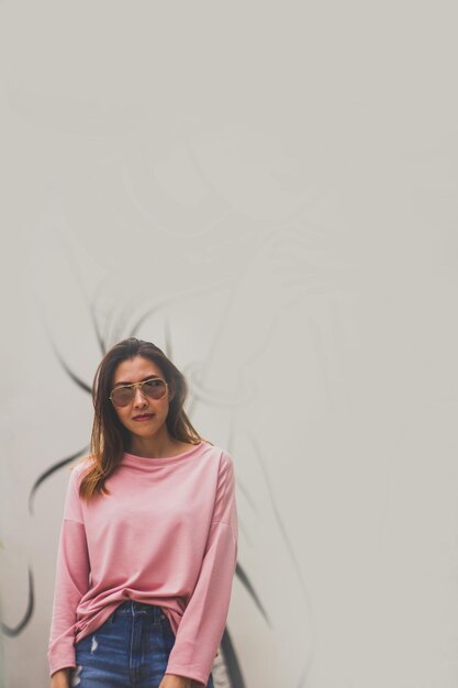 Photo portrait of a smiling young woman standing against wall