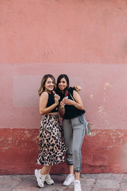 Photo portrait of a smiling young woman standing against wall