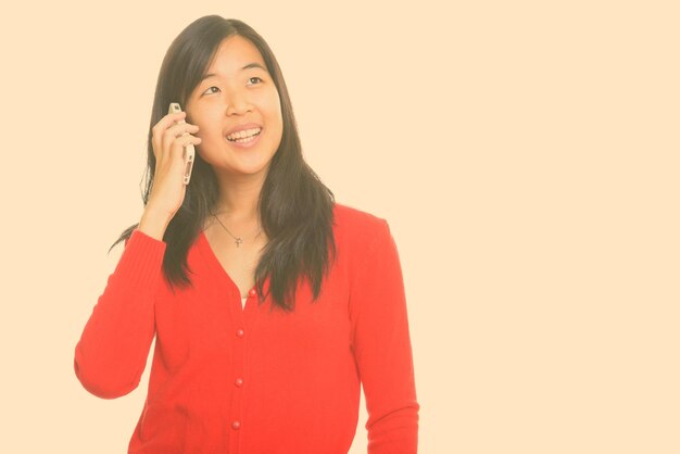 Portrait of smiling young woman standing against white background