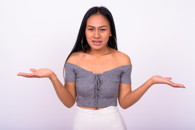 Portrait of smiling young woman standing against white background