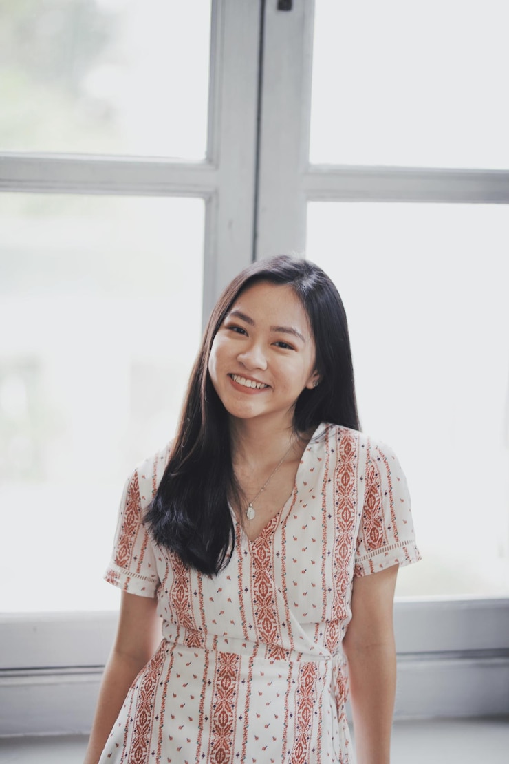 Photo 창문 에 서 있는 미소 짓는 젊은 여성의 초상화