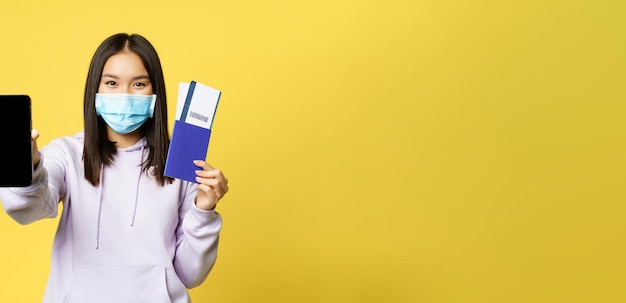 Portrait of smiling young woman standing against yellow background