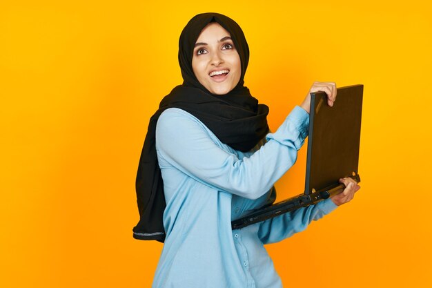 Portrait of smiling young woman standing against yellow background