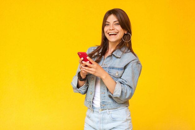 Portrait of smiling young woman standing against yellow background