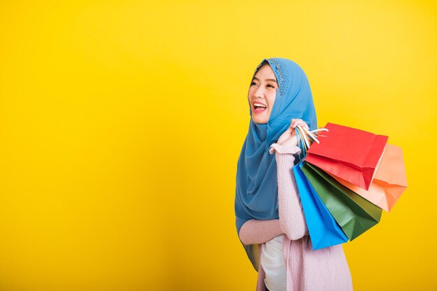 Portrait of smiling young woman standing against yellow background