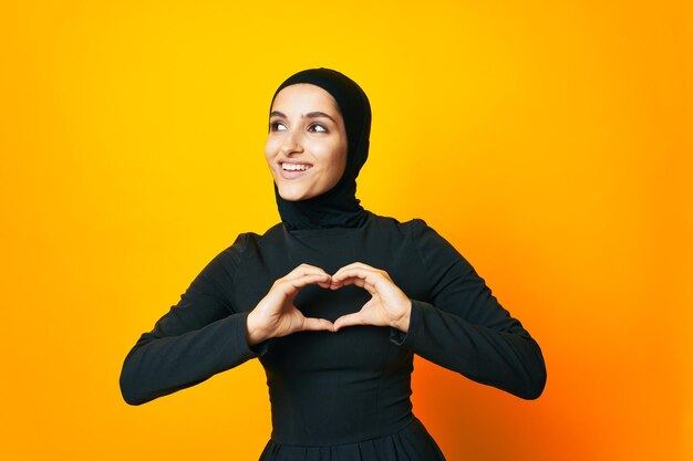 Portrait of smiling young woman standing against yellow background