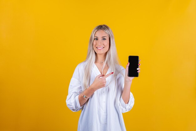 Portrait of a smiling young woman standing against yellow background