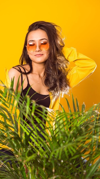 Portrait of smiling young woman standing against yellow plants