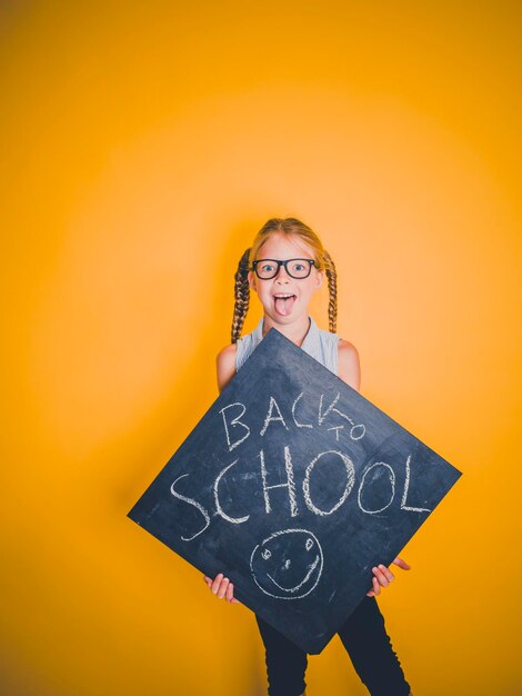 Portrait of smiling young woman standing against yellow wall