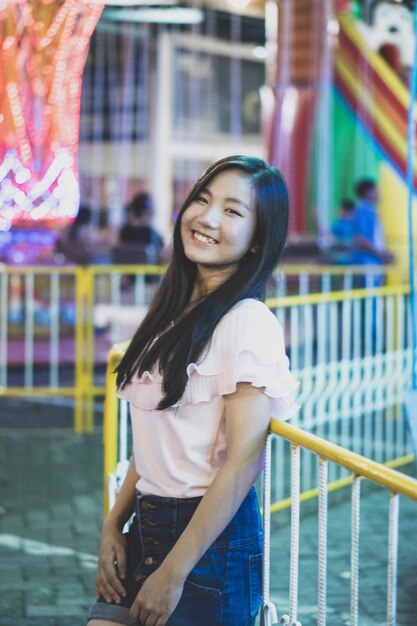 Photo portrait of smiling young woman standing at amusement park during night