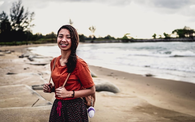 Foto ritratto di una giovane donna sorridente in piedi sulla spiaggia