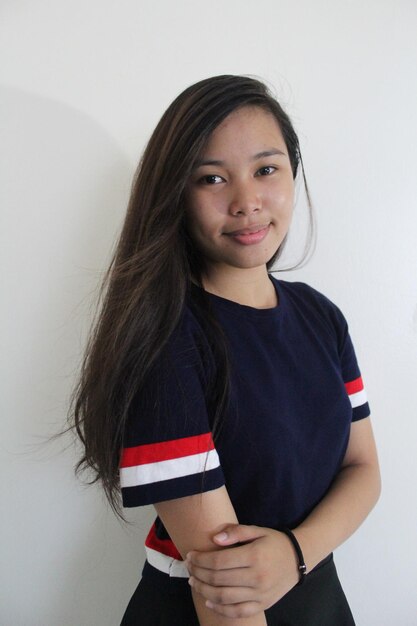 Photo portrait of smiling young woman standing by wall