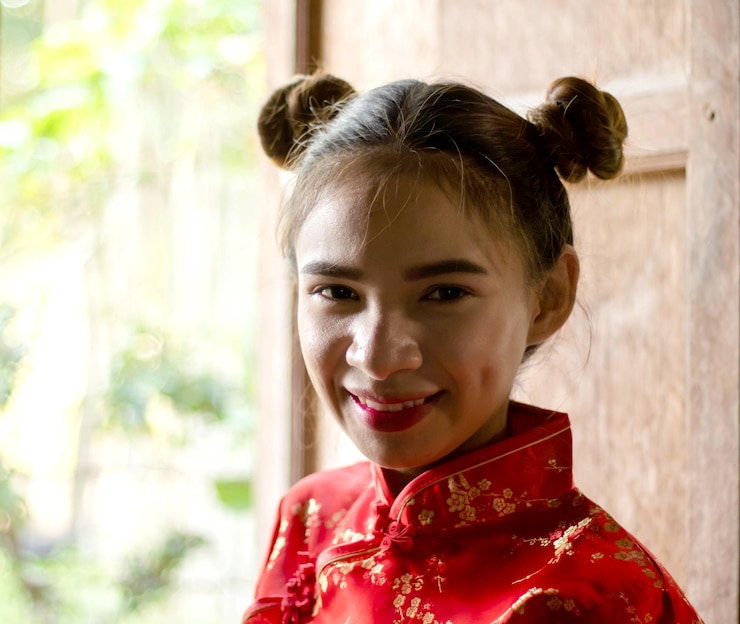 Photo portrait of smiling young woman standing by window