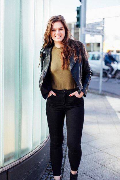 Portrait of smiling young woman standing on footpath