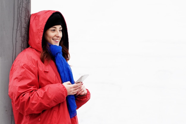 Portrait of smiling young woman standing on mobile phone in winter