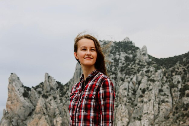 Foto ritratto di una giovane donna sorridente in piedi su una roccia contro il cielo