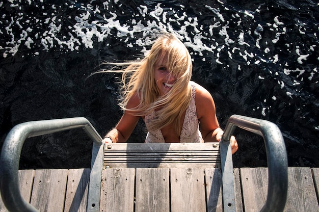 Photo portrait of smiling young woman standing on steps against sea