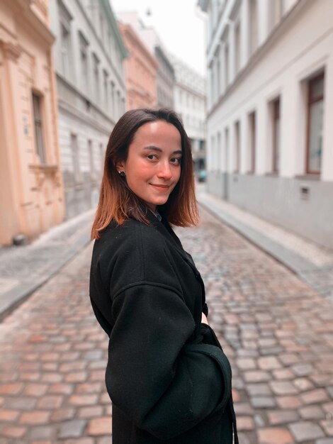 Photo portrait of smiling young woman standing on street amidst buildings