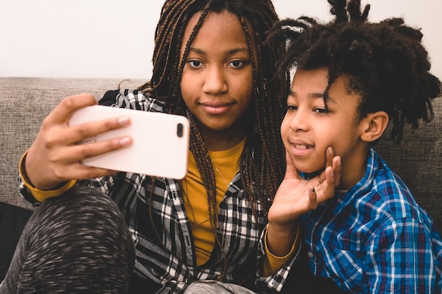 portrait of smiling young woman taking selfie with brother through smart phone