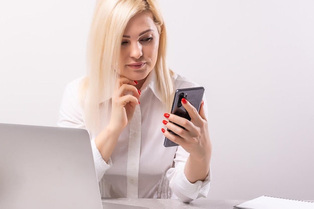 Portrait of a smiling young woman using laptop and mobile phone