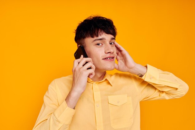 Portrait of smiling young woman using mobile phone against yellow background