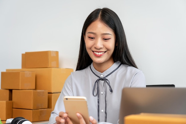 Portrait of smiling young woman using mobile phone while standing against white background