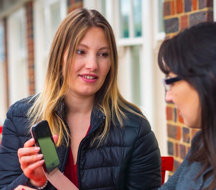 Photo portrait of smiling young woman using mobile phone