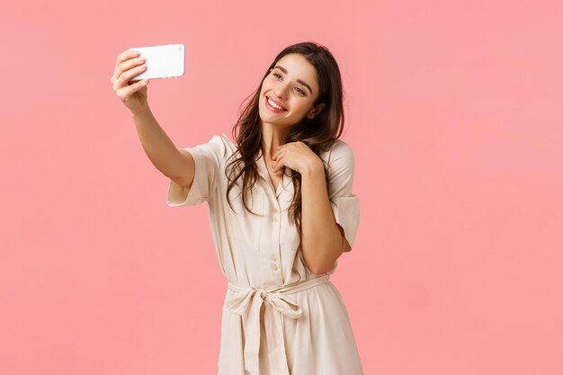 Portrait of smiling young woman using phone against pink background