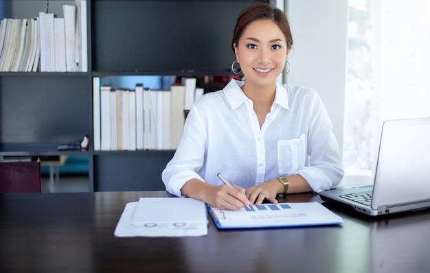 Portrait of smiling young woman using phone on table