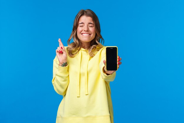 Portrait of a smiling young woman using smart phone against blue sky