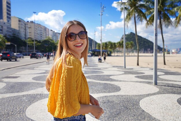 Photo portrait of smiling young woman walking along copacabana beach promenade rio de janeiro brazil