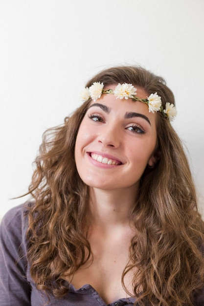 Photo portrait of smiling young woman wearing flowers at home