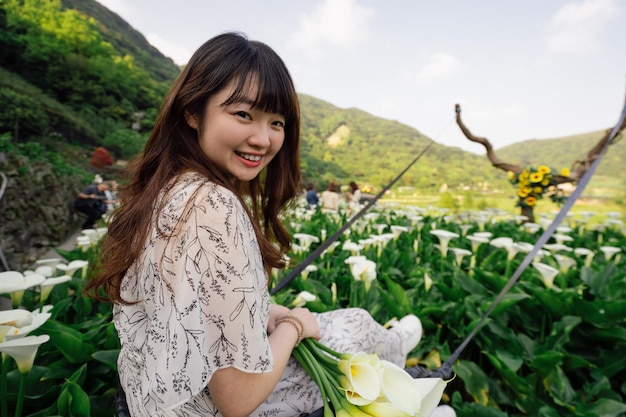 畑で花を握っている帽子をかぶった笑顔の若い女性の肖像画