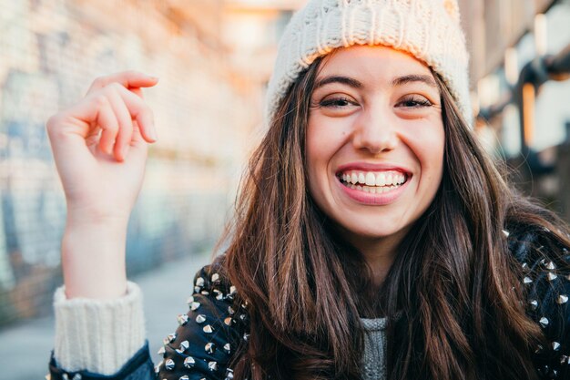 Photo portrait of smiling young woman wearing knit hat in city