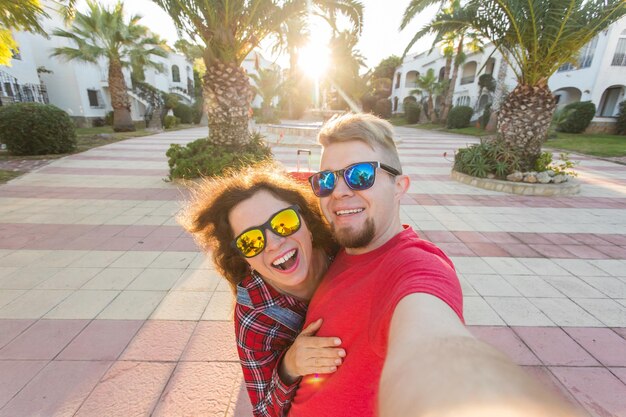 Portrait of smiling young woman wearing sunglasses against trees