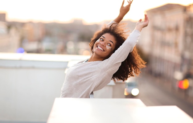 Photo portrait of smiling young woman with arms raised standing in cafe