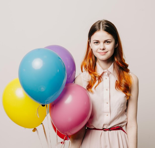 Portrait of smiling young woman with balloons against white background