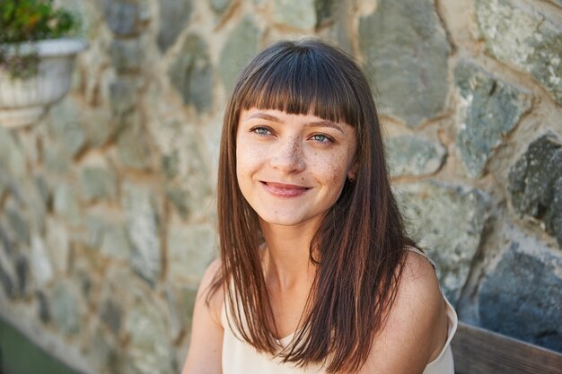 Portrait of a smiling young woman with freckles on her face in the summer on a city street