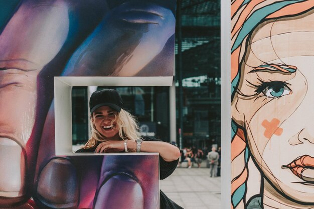 Photo portrait of smiling young woman with graffiti wall