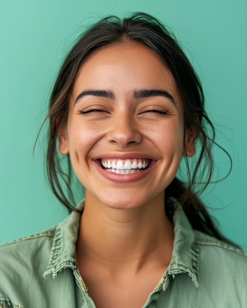 Portrait of a smiling young woman with her eyes closed on a green background