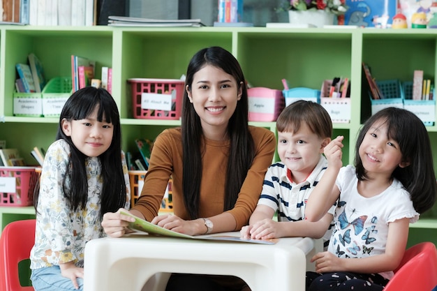Portrait of smiling young woman with students sitting in classroom
