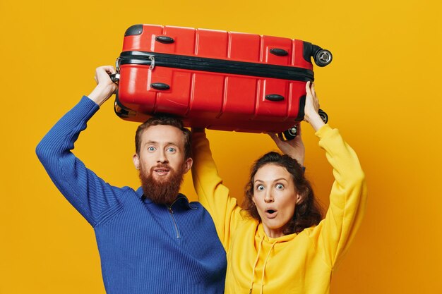 Portrait of smiling young woman with teddy bear in suitcase against yellow background