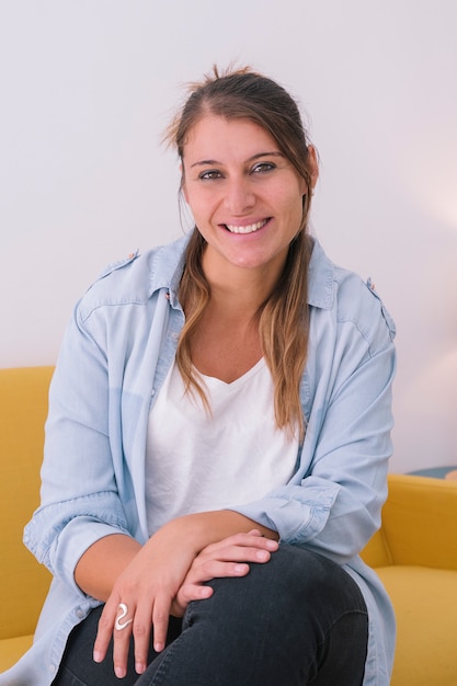 Photo portrait of smiling young woman on yellow couch