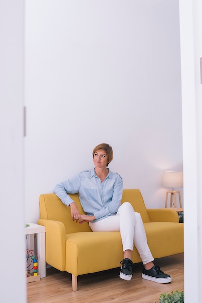 Portrait of smiling young woman on yellow couch